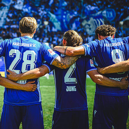 KSC-Spieler Arm in Arm vor den Fans