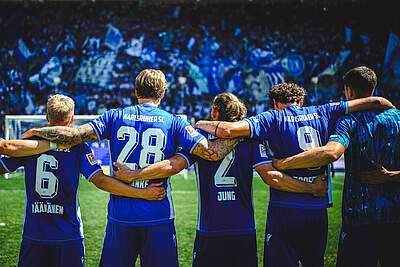 KSC-Spieler Arm in Arm vor den Fans