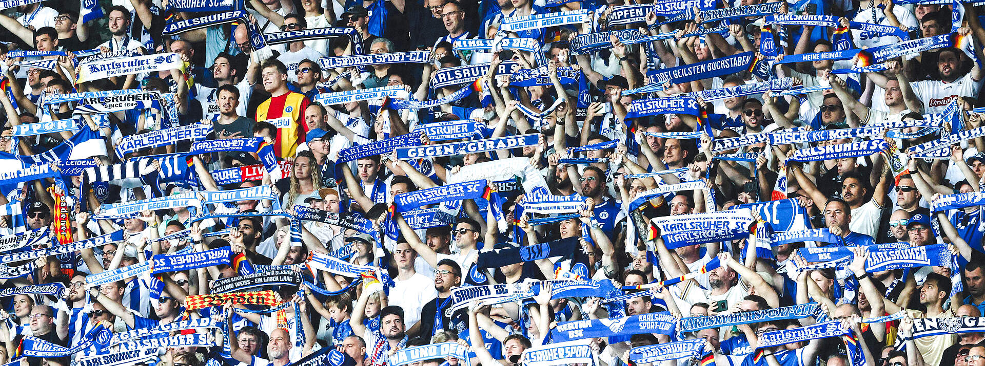 Fans halten ihre Schals im Stadion hoch.