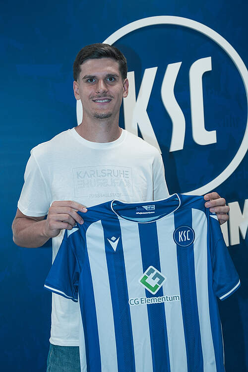 Igor Matanović hält ein KSC-Heimtrikot in der Hand