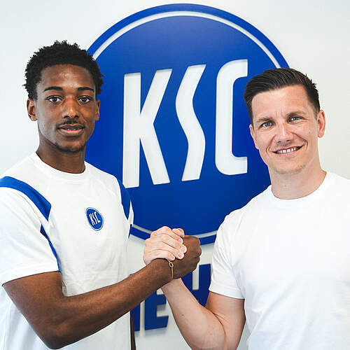 Kimberly Ezekwem und Thomas Konrad machen Handschlag vor dem KSC-Logo.