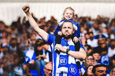 Ein KSC-Fan im BBBank Wildpark trägt seine Tochter auf den Schultern