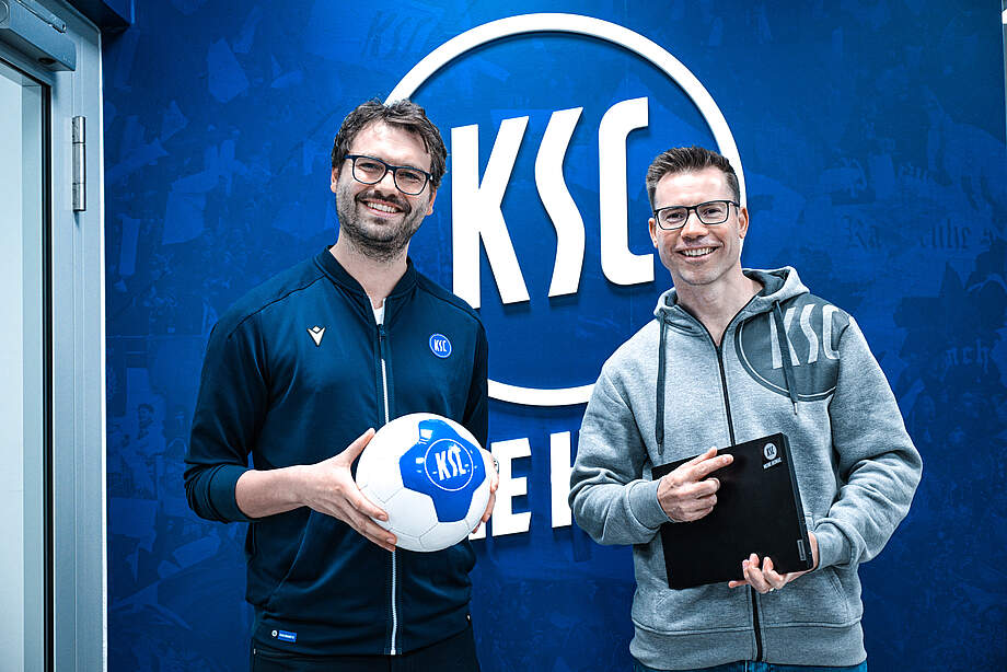 Die Verantwortlichen des KSC und der AfB gGmbH vor dem KSC-Logo