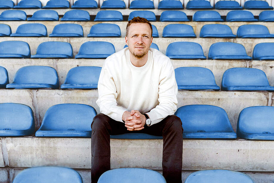Maximilian Senft sitzt auf der Tribüne eines Stadions.