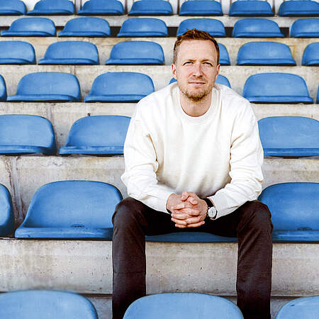Maximilian Senft sitzt auf der Tribüne eines Stadions.