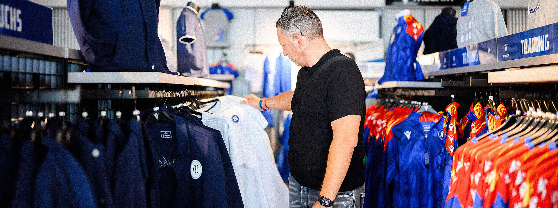 Ein Mann schaut sich in der KSC-FanWelt ein T-Shirt an