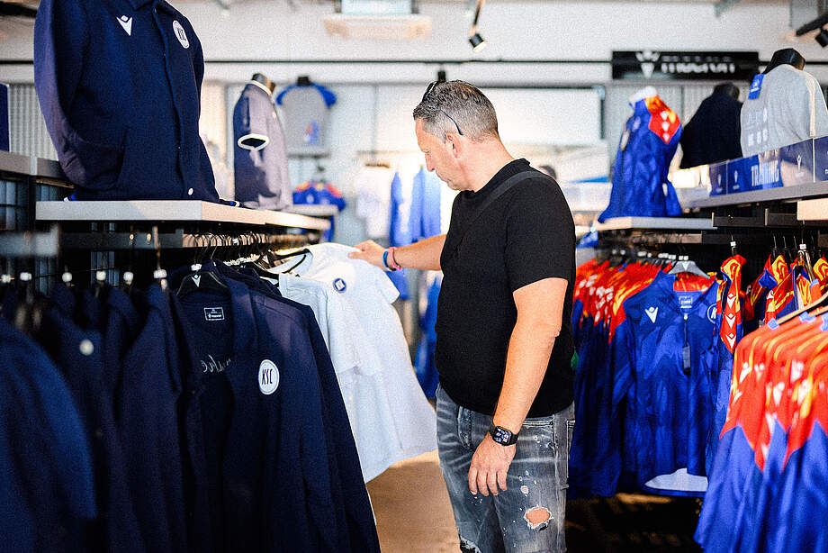 Ein Mann schaut sich in der KSC-FanWelt ein T-Shirt an
