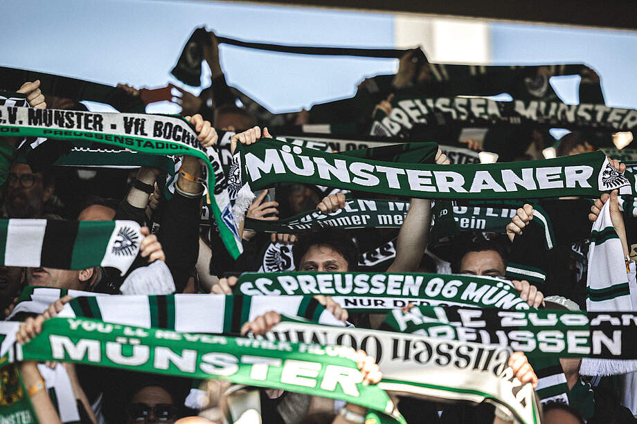 Münsteraner Fans halten Schal hoch