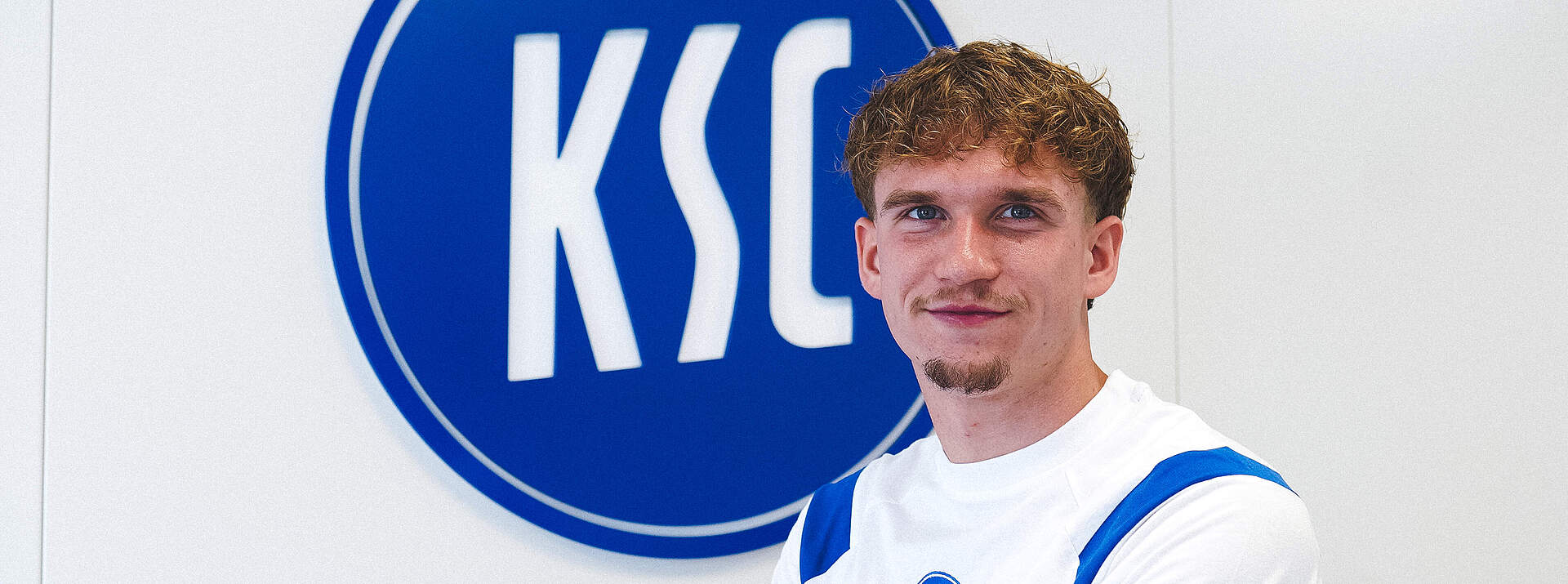 Julian Gerold vor dem KSC-Logo