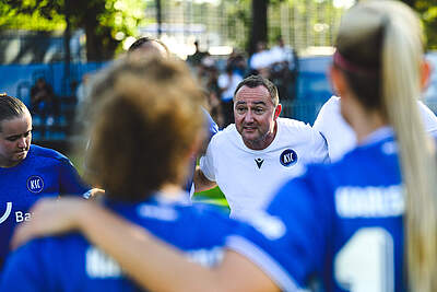Trainer Christopher Holzer spricht im Teamkreis zu seiner Mannschaft.