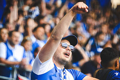 Ein Fan im BBBank Wildpark reckt seine Faust in die Höhe.