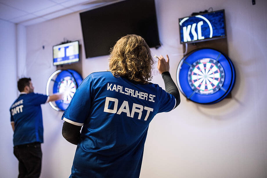 Ein KSC-Spieler wirft einen Dart auf die Scheibe.