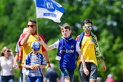 Ein Junge im KSC-Trikot schwenkt eine blau-weiße "Meine Heimat."-Fahne