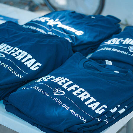 T-Shirts vom KSC-Helfertag ausgebreitet auf einem Tisch.