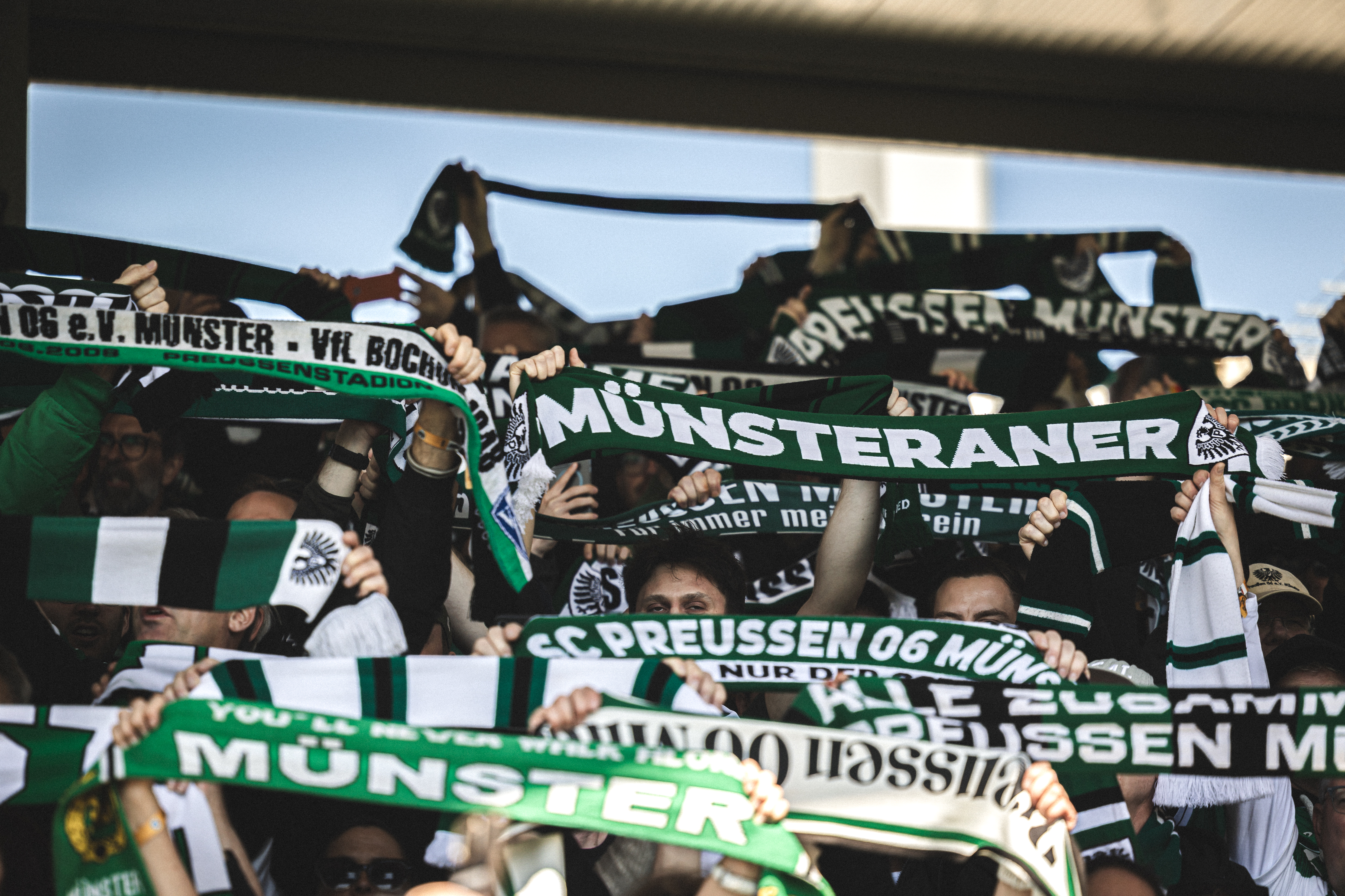 Münsteraner Fans halten Schal hoch