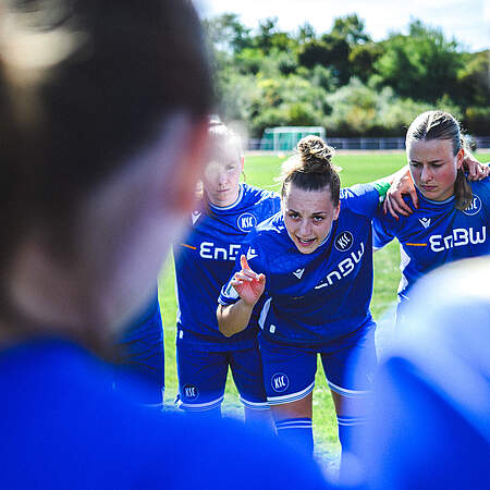 Die KSC-Frauen bilden einen Mannschaftskreis und eine Spielerin hebt ihre Hand und spricht zur Mannschaft.